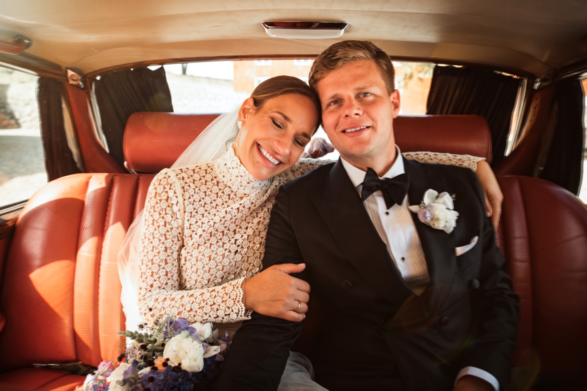 Vicky and Seb sharing a joyful moment in their wedding car